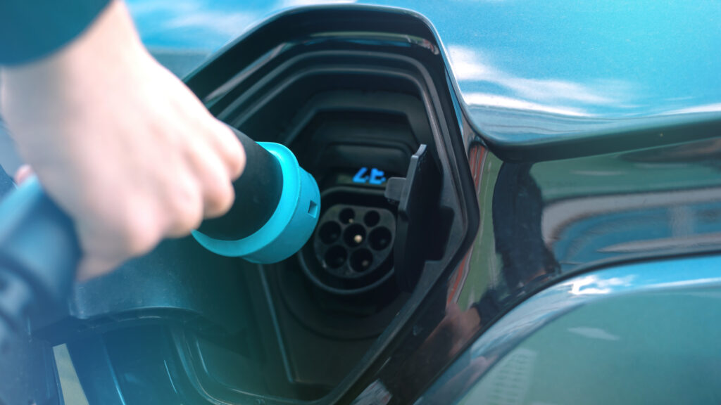 Man plugging charger into electric car charge station